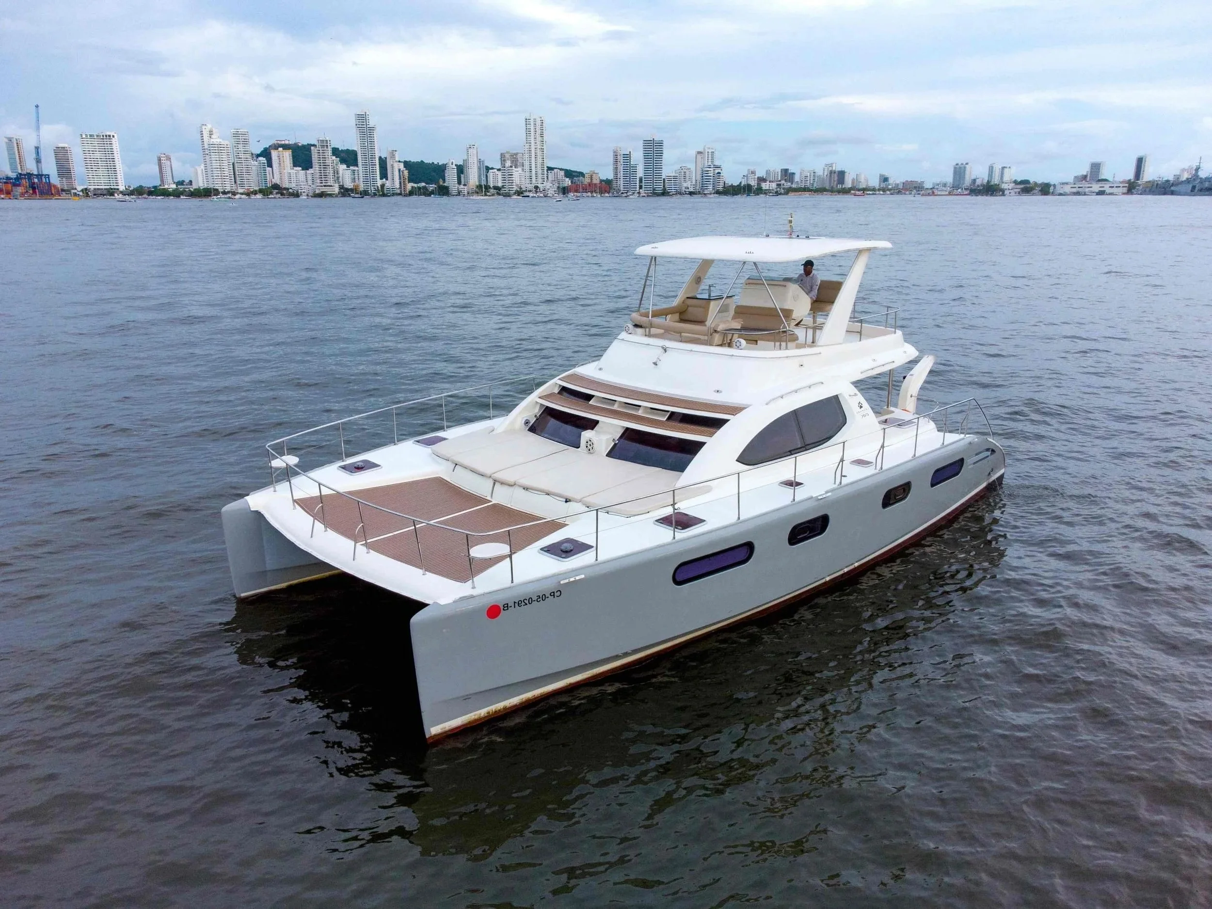 A white luxury yacht floating on water with a city skyline in the background, featuring tall buildings and skyscrapers.