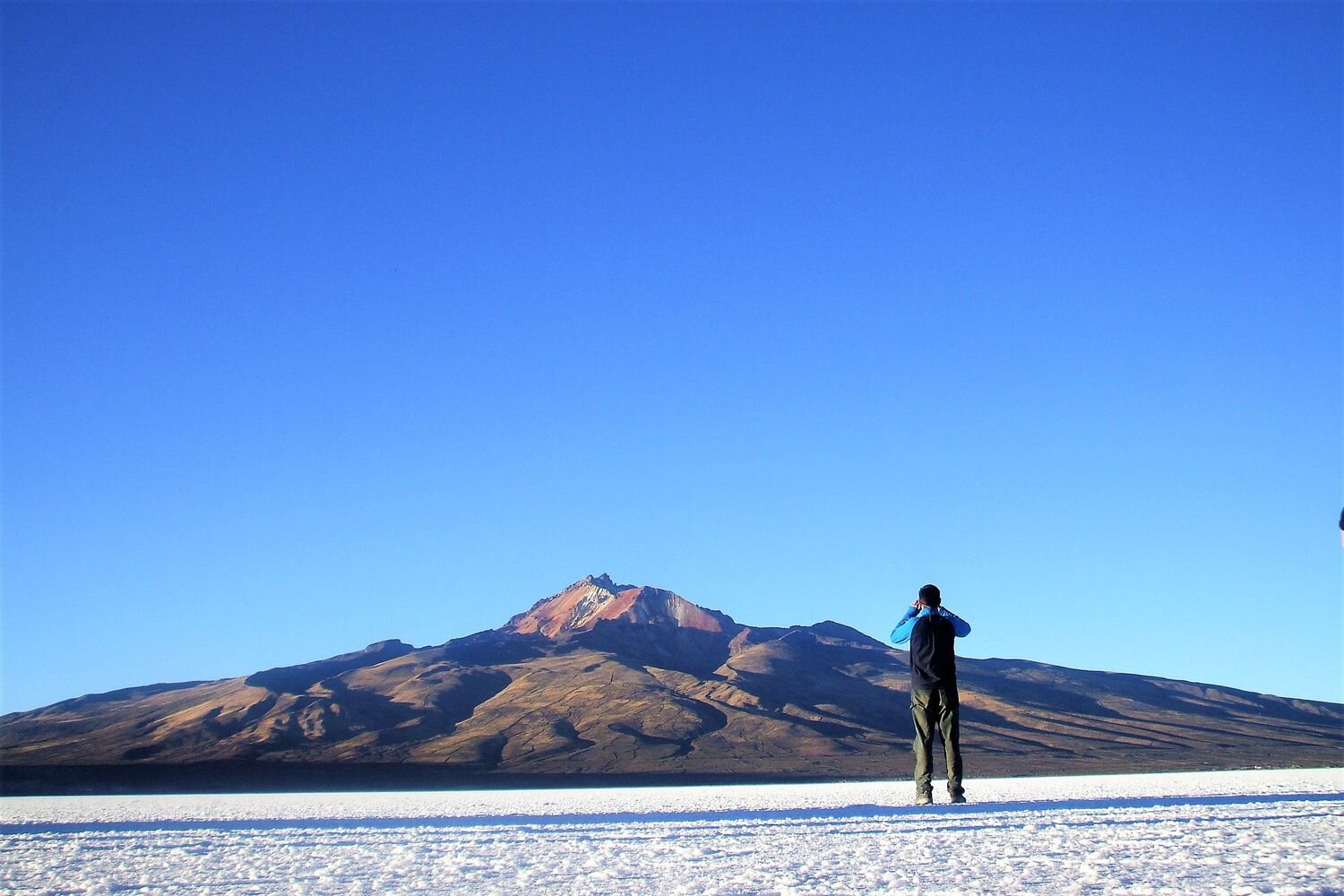  A visitor in the middle of the Uyuni Salt Flat with the Tunupa volcano in the background. Bolivia 