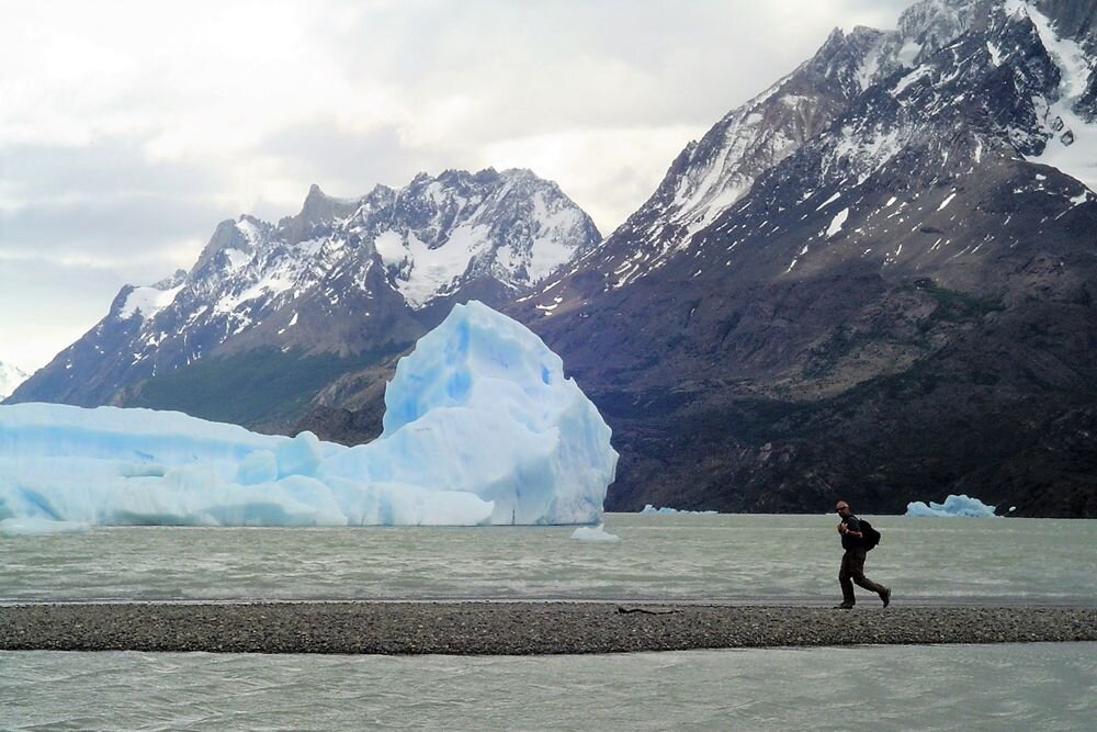  Hiking at the shores of Lake Grey, with an iceberg stranded on its way to the river. Torres del Paine, Chile 