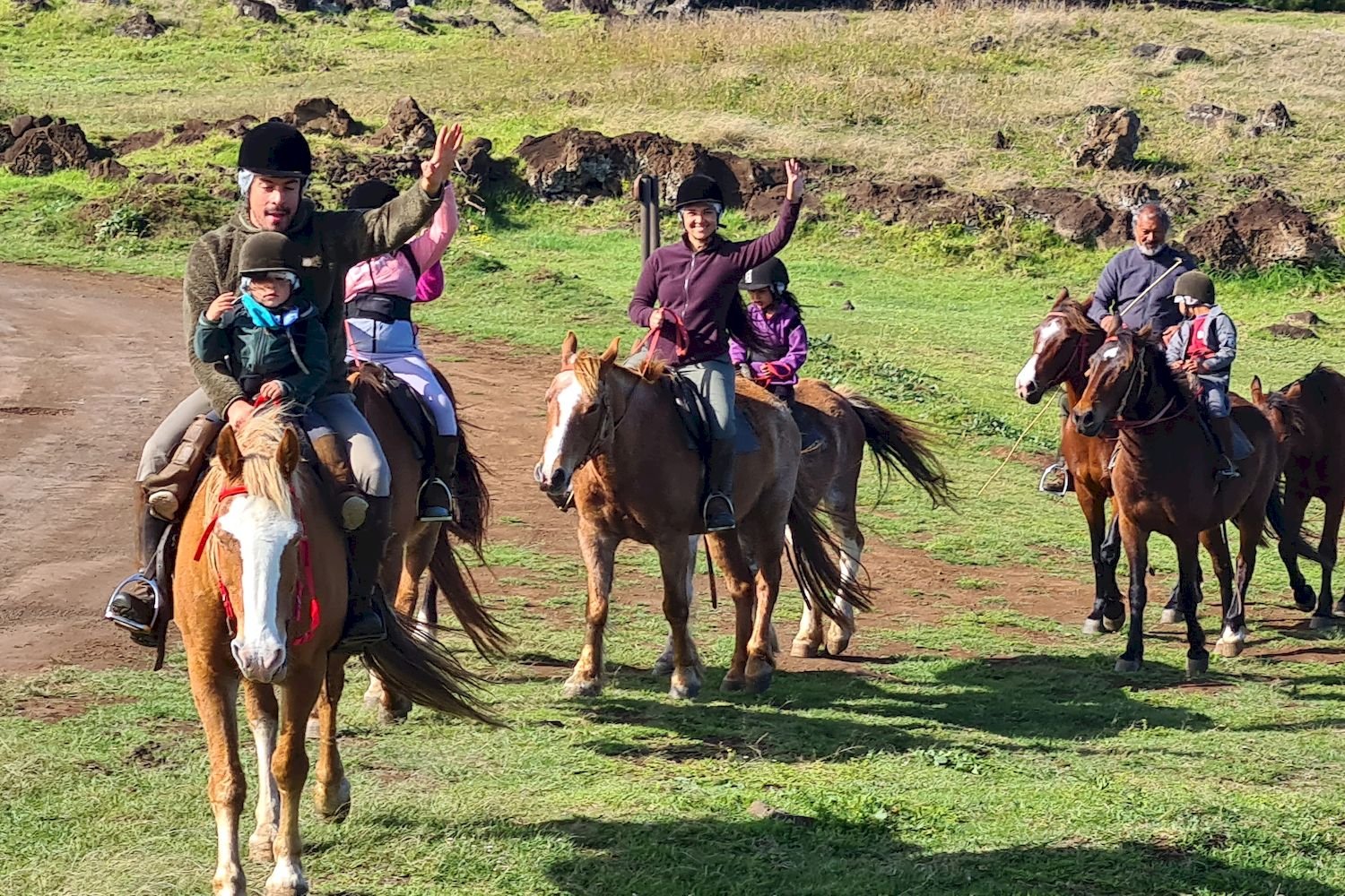 Families riding horses through the grassy hills of Easter Island.