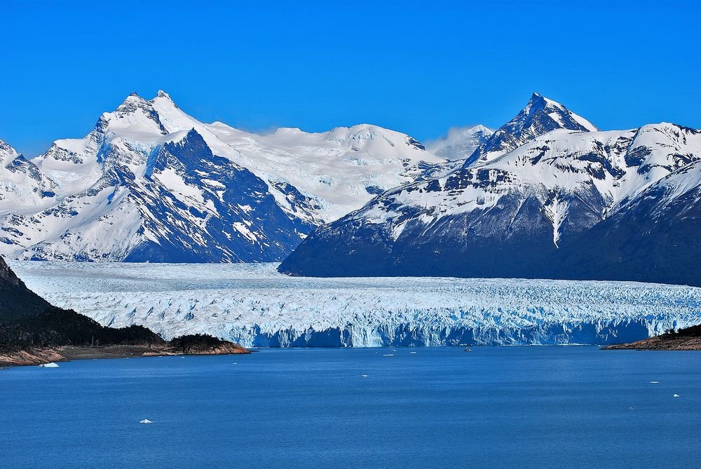Panoramic view of the vast Perito Moreno Glacier framed by the Andes mountains, a highlight of any Patagonia Chile Argentina tour.