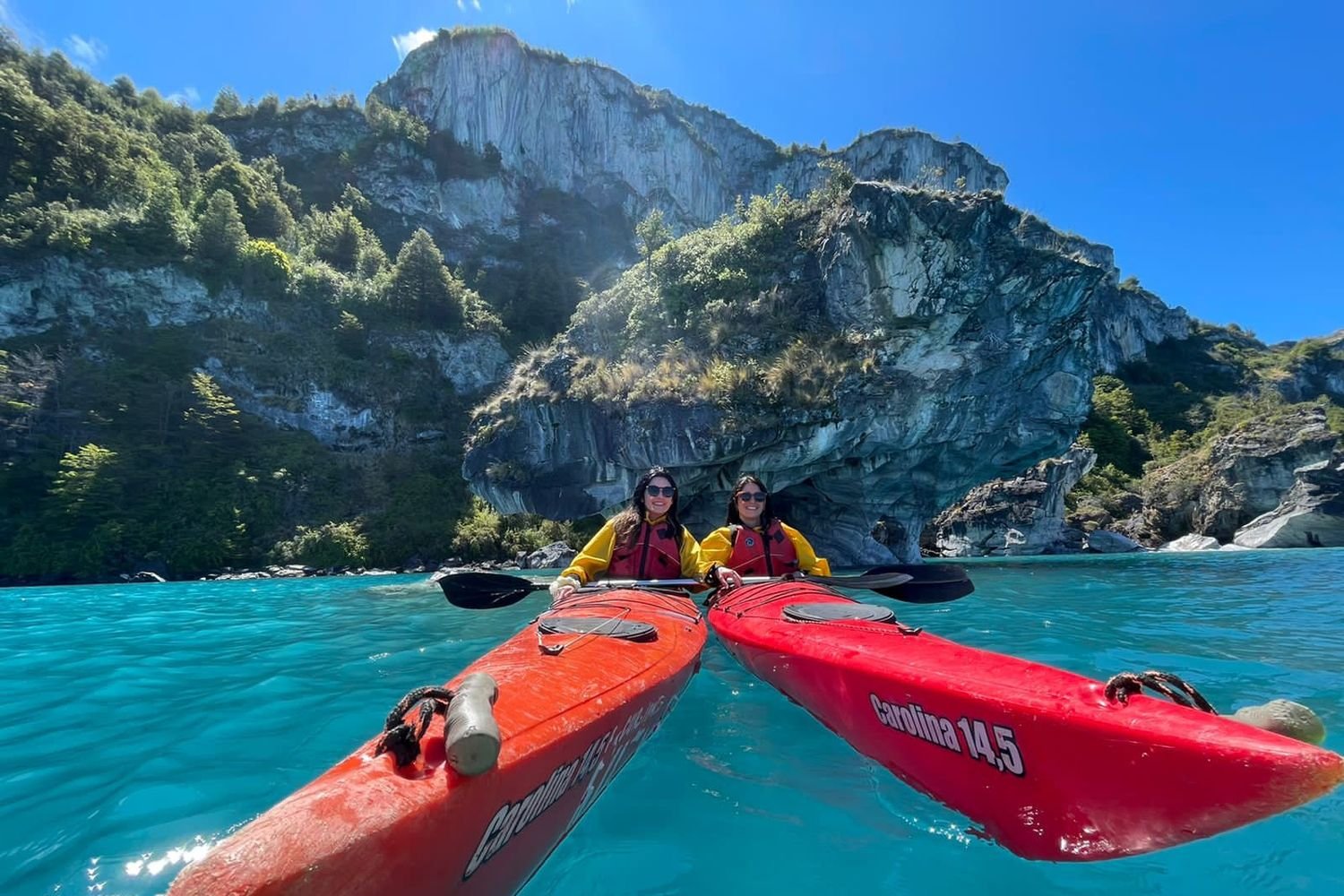 Two travelers kayaking in the turquoise waters of the Marble Caves during a Carretera Austral self-drive tour in Chile.