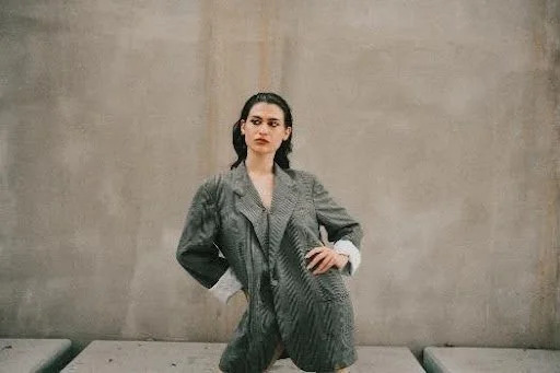 a woman with dark hair in an oversized blazer