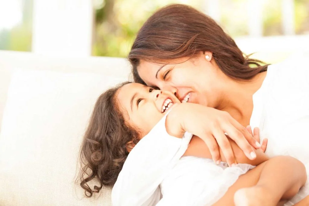 Happy mum hugging laughing young daughter