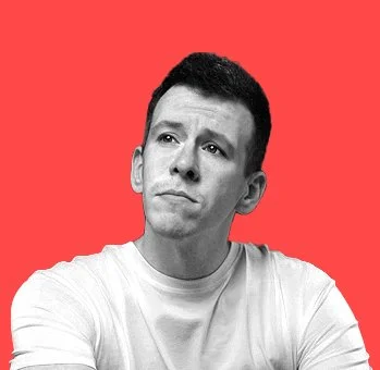 Black and white photo of a young man with short dark hair wearing a light-colored T-shirt, looking thoughtful against a red background.