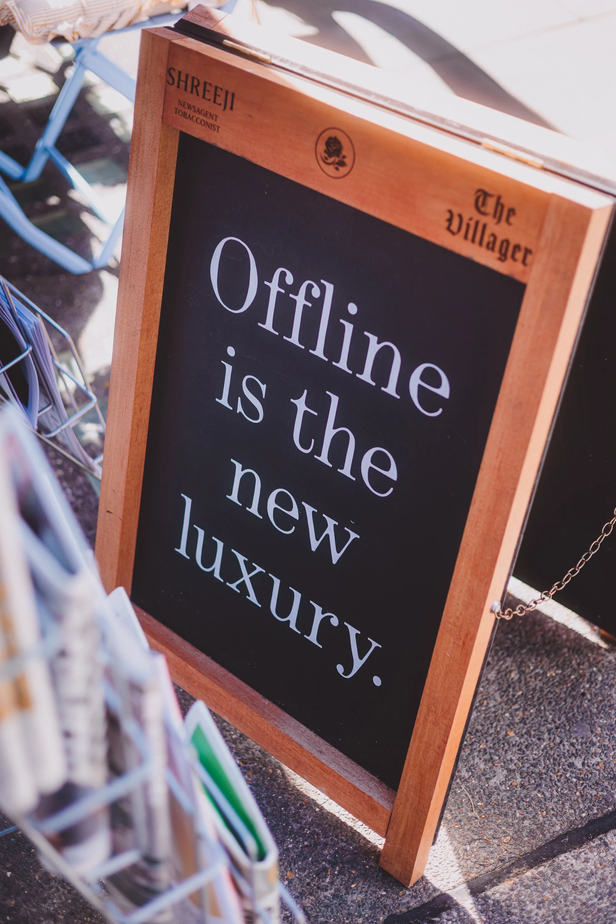Photograph of a wooden sign outside of Shreeji Newsagants in Marylebone, London