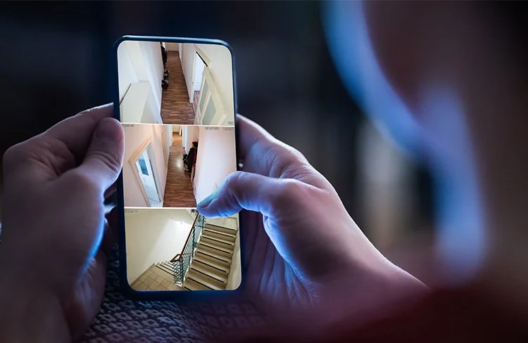 Spartanburg homeowner remotely viewing live indoor security camera feeds on a smartphone.