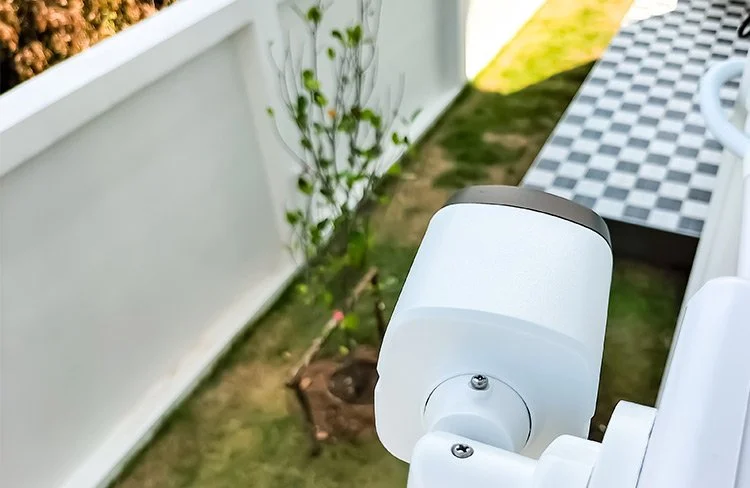 White outdoor security camera monitoring the backyard of a Spartanburg, SC home.