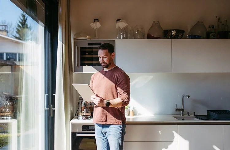 Homeowner using a tablet to manage smart home features from a kitchen in Greenville, SC