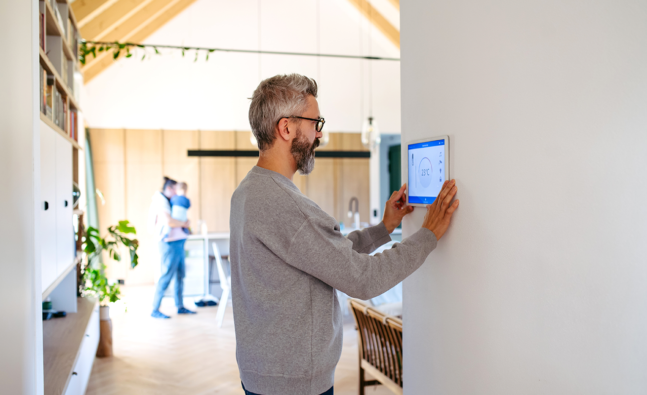 Man using a wall-mounted smart home control panel.