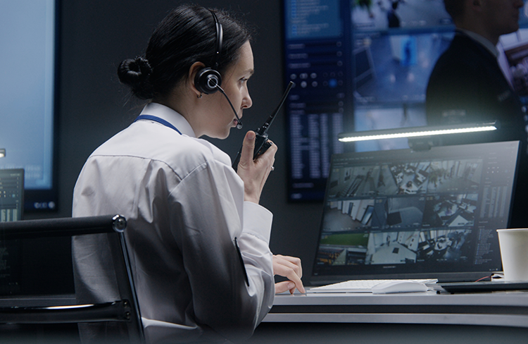 Professional security monitoring center operator reviewing surveillance camera feeds for customers in Greenville, SC.