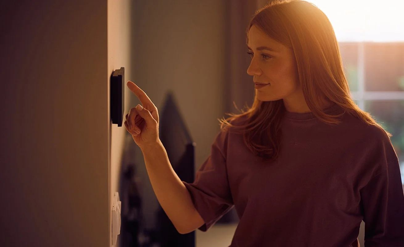 Spartanburg homeowner using a wall-mounted touchscreen to control her smart home system.