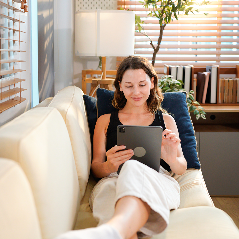 Woman using a tablet to control smart home features from her living room in Greenville, SC