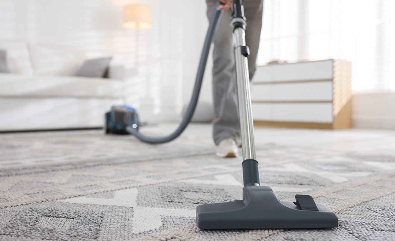 Person vacuuming a bright modern living room.