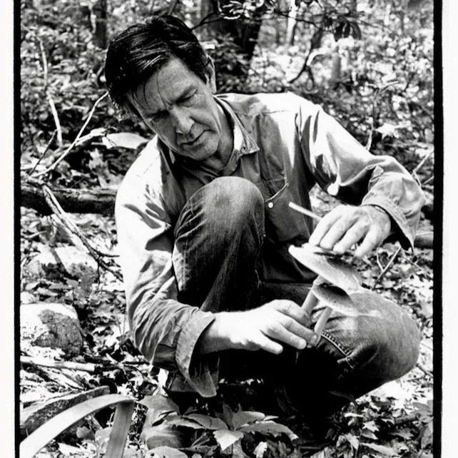 Middle-aged man crouched holding mushrooms