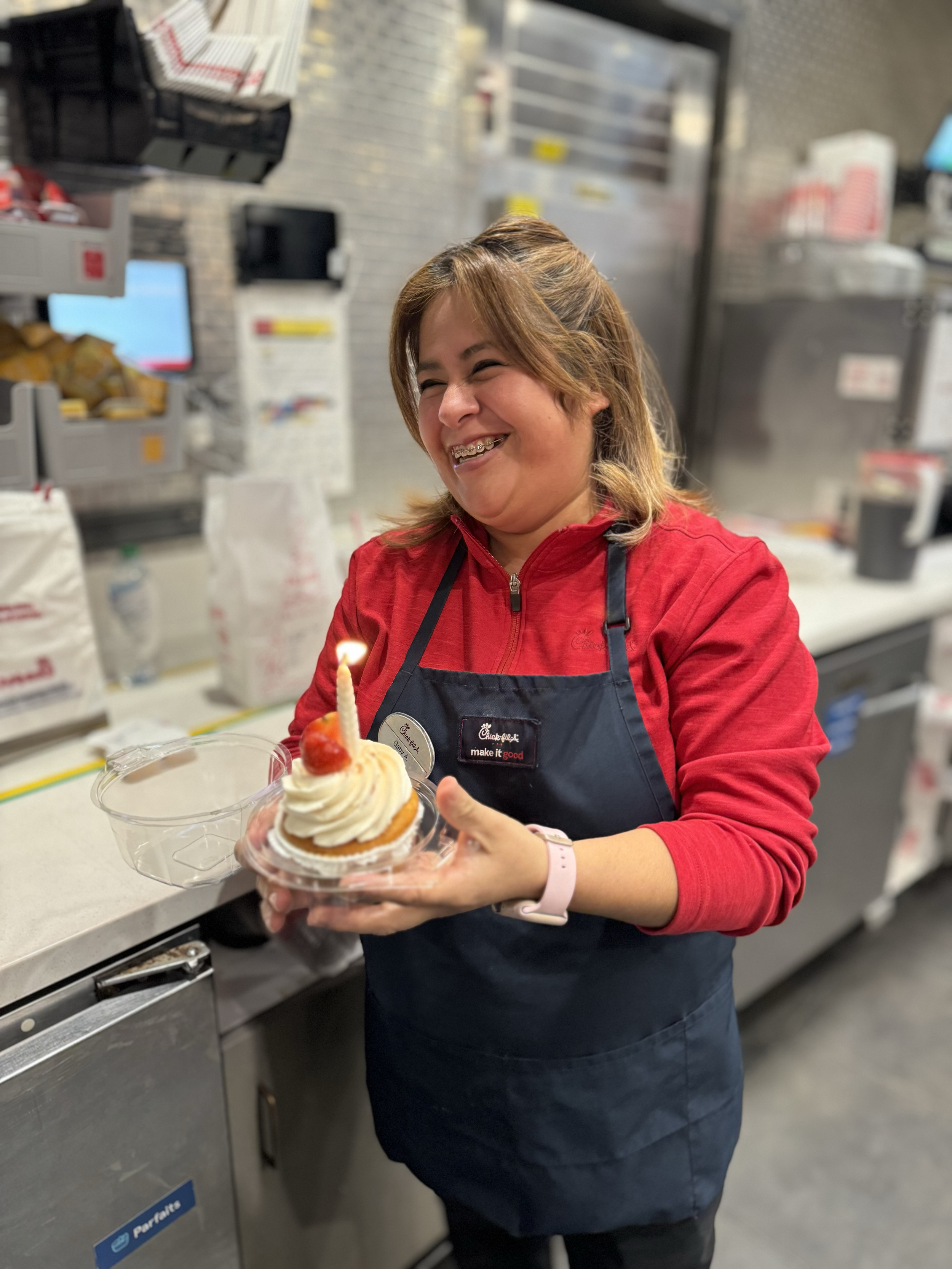 Chick-fil-A female team member holding a cupcake with a candle.