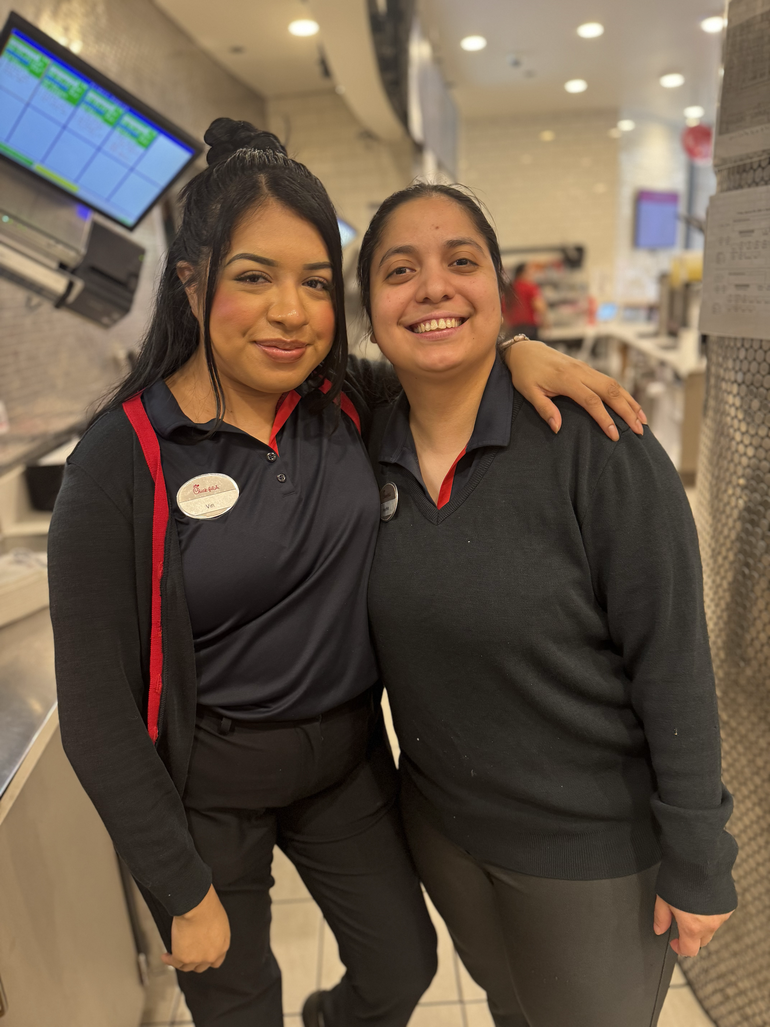 Two Chick-fil-A Chicago female team members smiling at the camer with their arms around eachother.