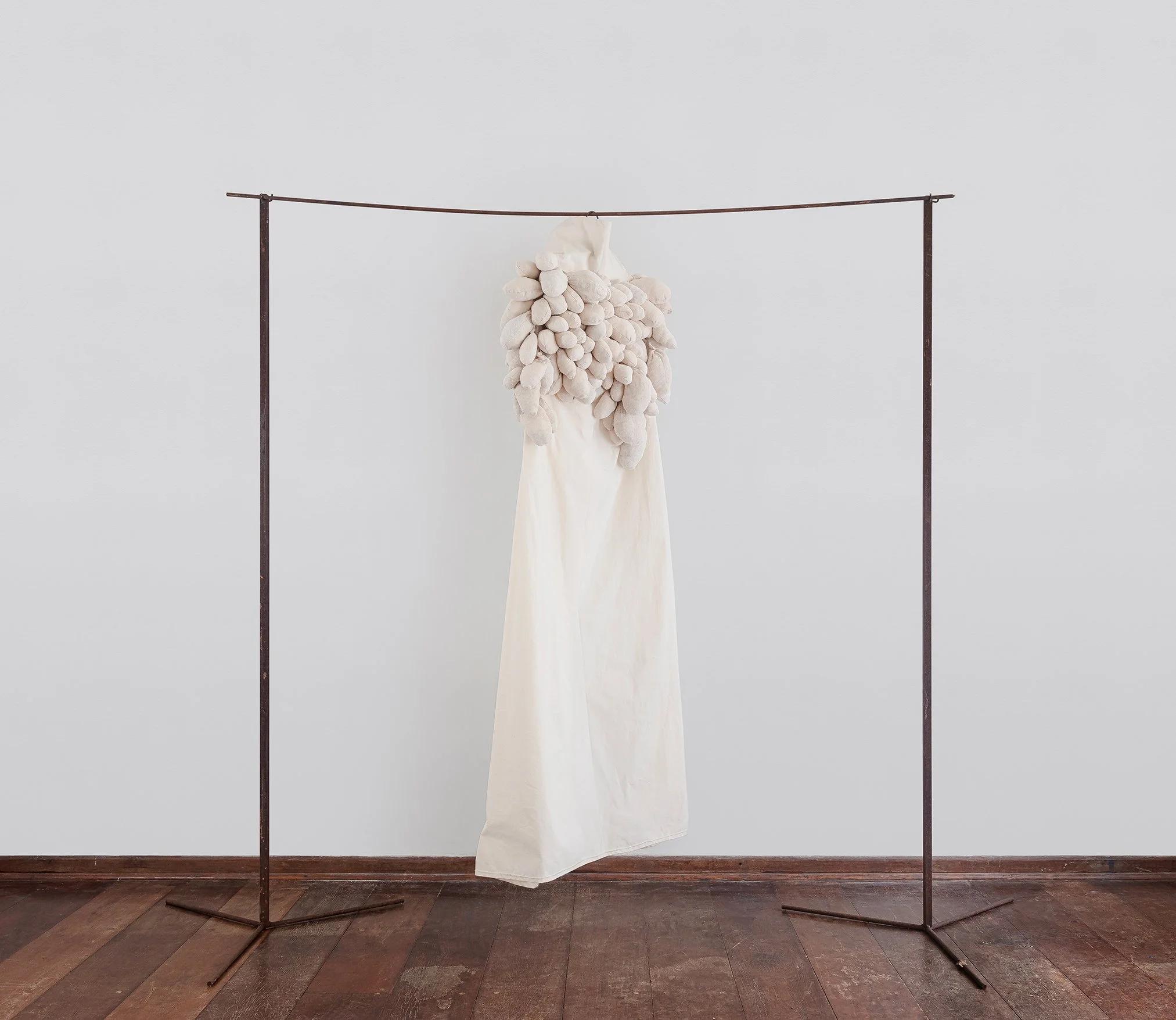  Flavia Renault, Manto, 2025. Algodão cru, pano de chão sem alvejar, estopa, linha de bordado, ferro e cabide antigo, 190 x 238 x 80 cm. 