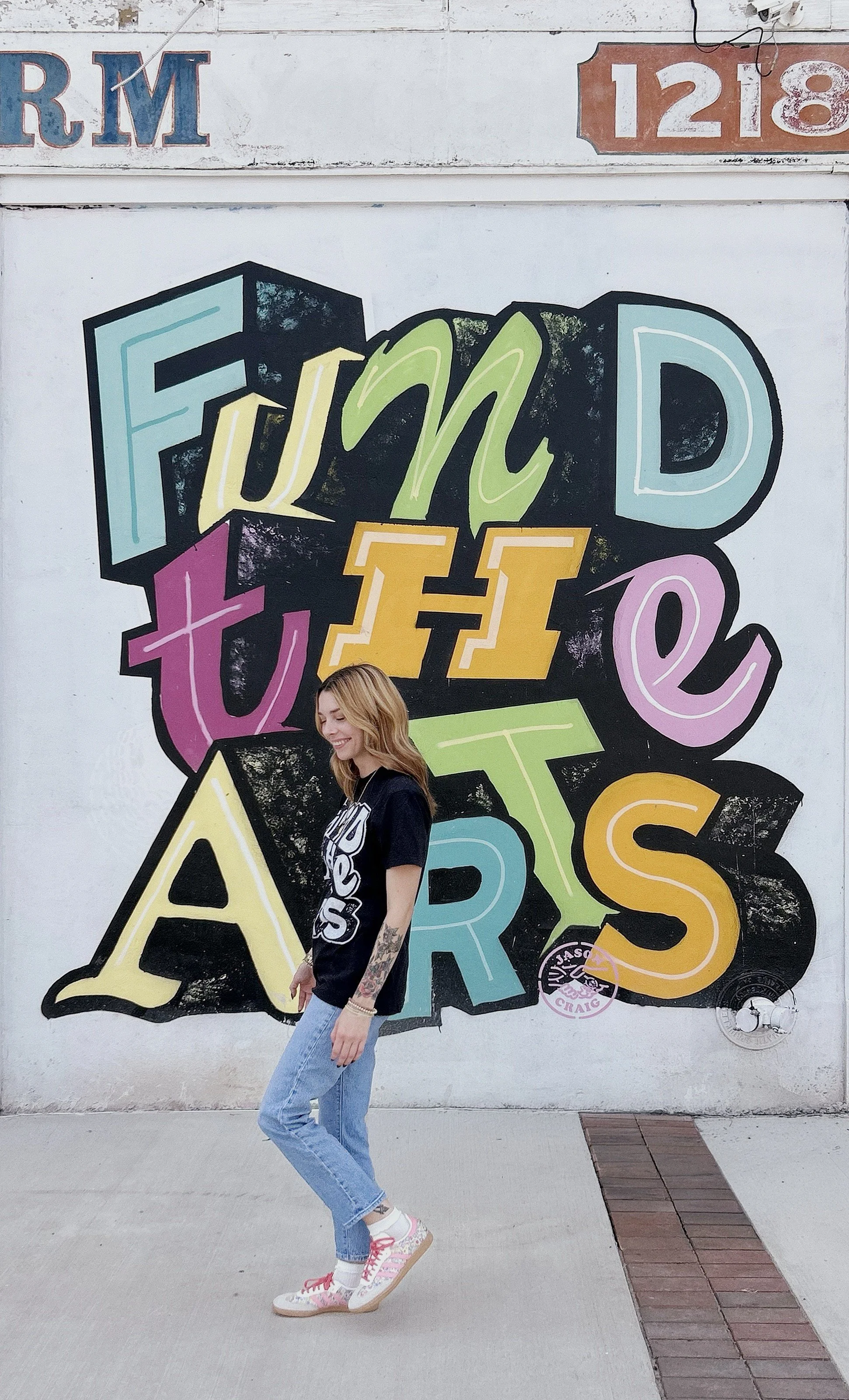 Fund the Arts mural in Augusta, Georgia, with colorful hand-painted lettering and a person wearing the matching shirt