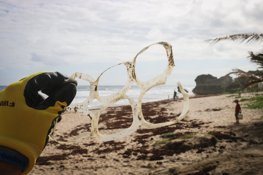 Plastic beer ring waste held on the beach