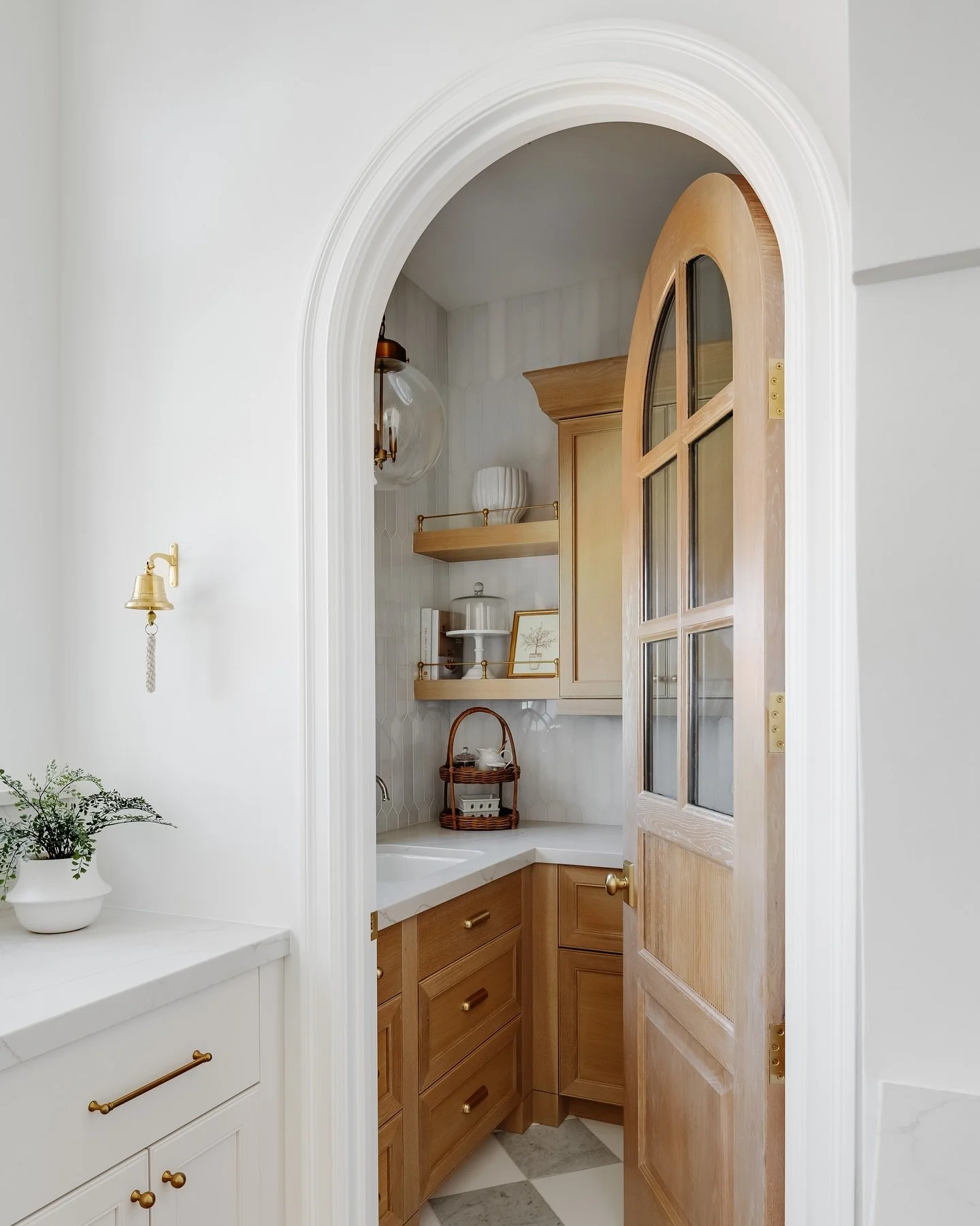 This dreamy butlers pantry is made up of oak cabinetry, a checkered marble floor, a marble backsplash, gold hardware &amp; a breathtaking view out of the most charming round window. Not to mention &mdash; the built in @gaggenauofficial coffee maker, 