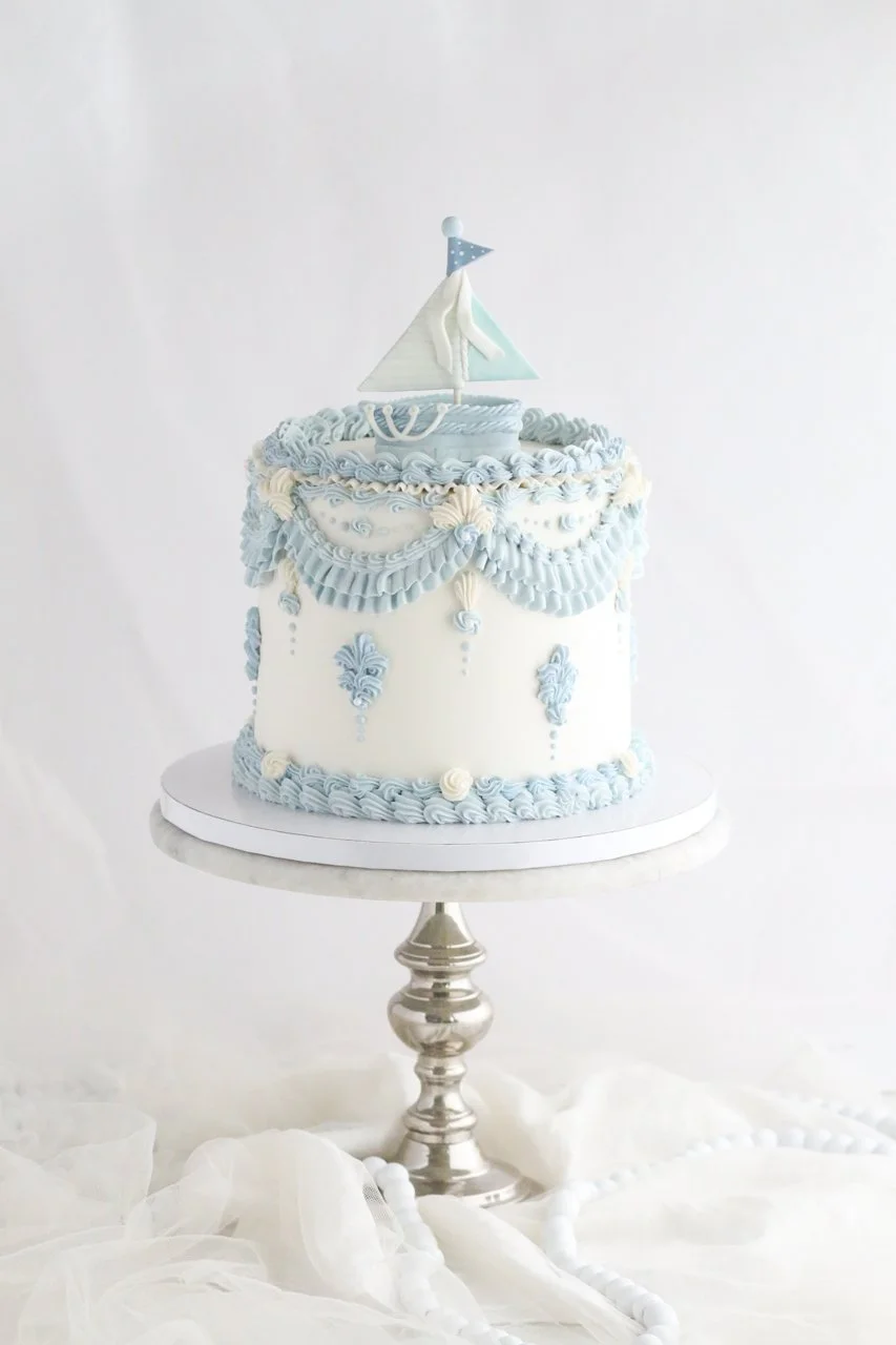 A Classic Blue Baby Shower Cake with a Personalized Sailboat Detail