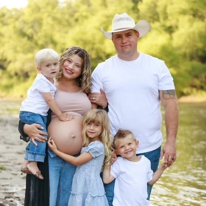 Family smiling by the river for maternity photos