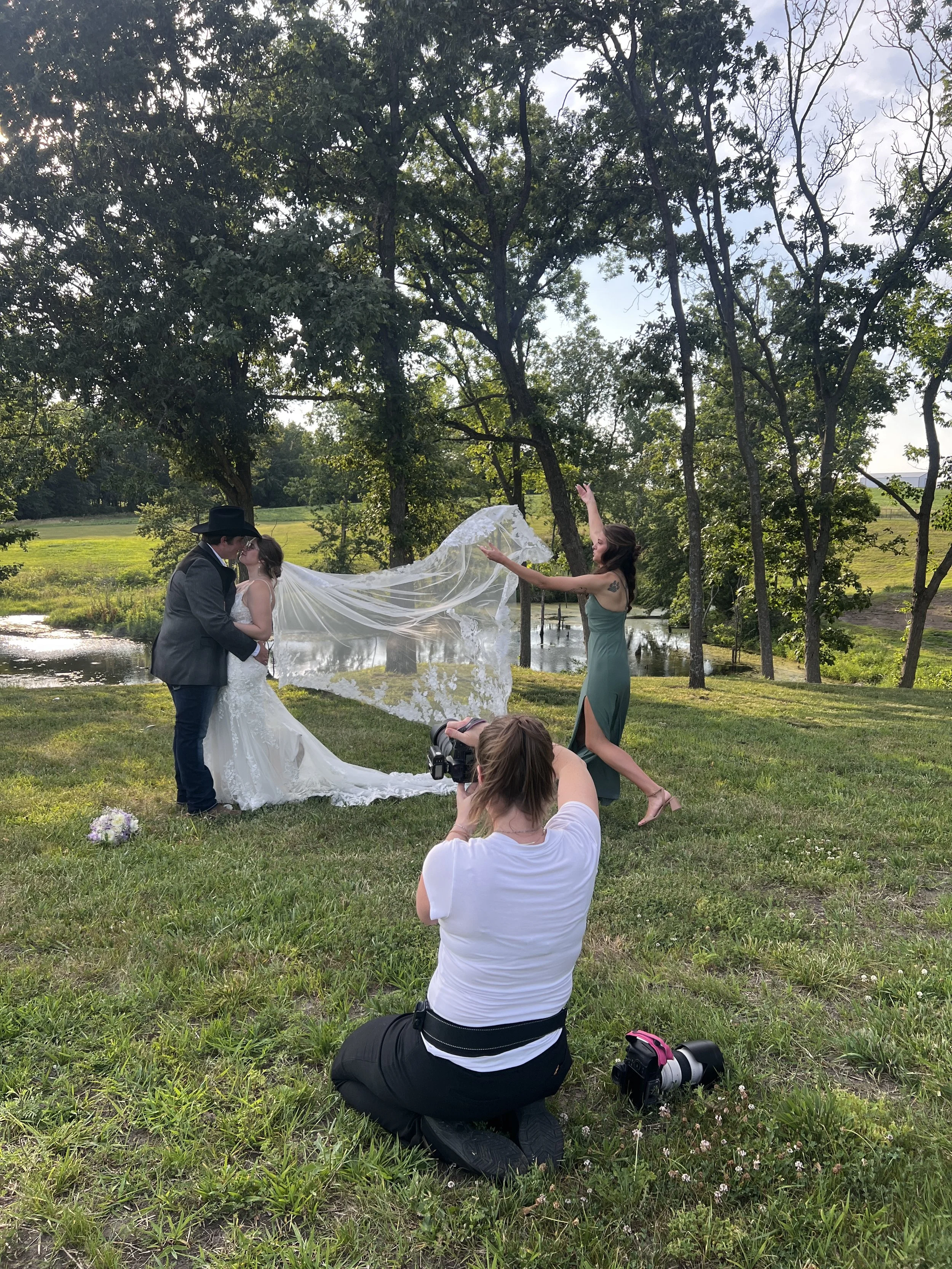 photoalli taking photos of a bride and groom near a pond