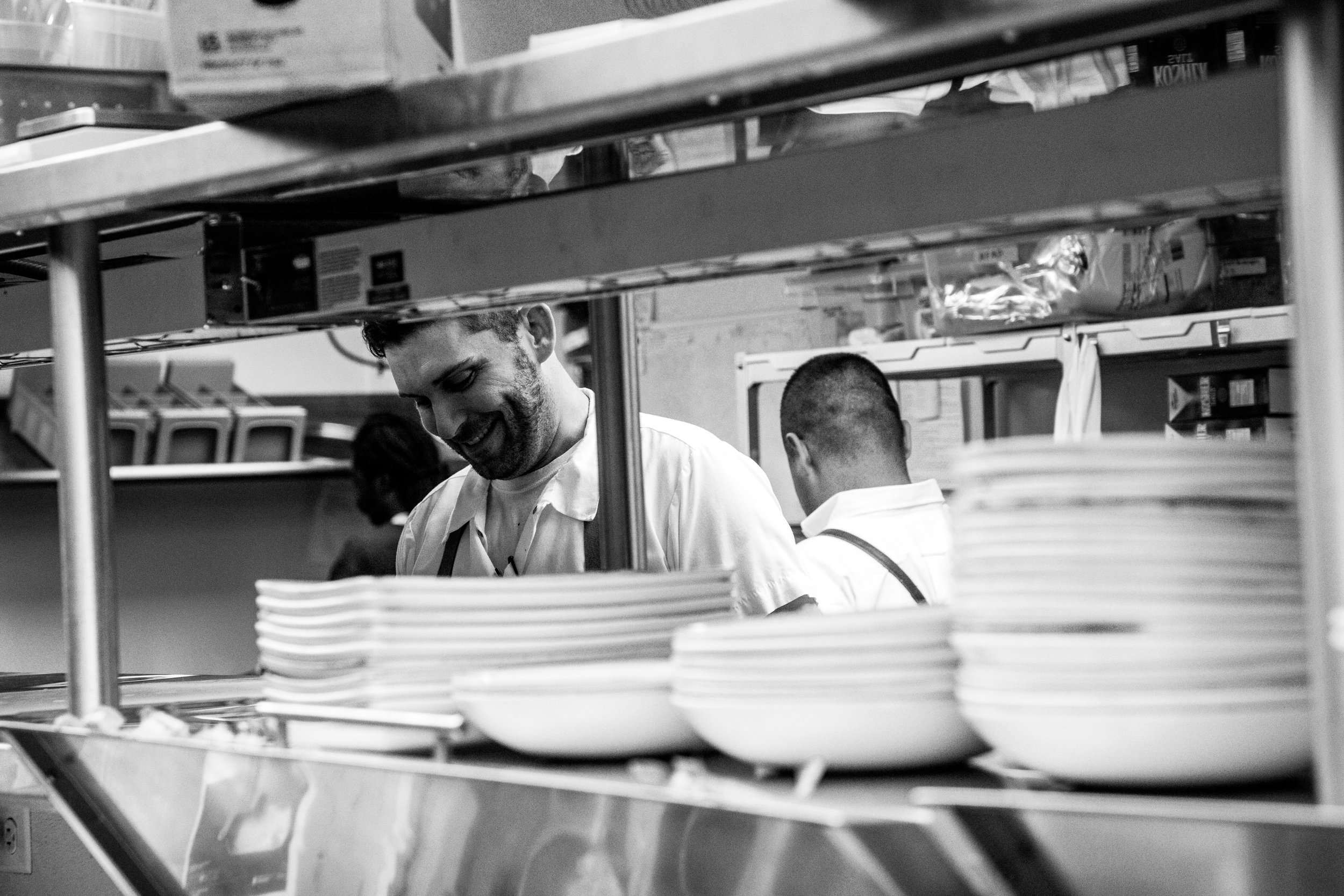 Line cook smiling as he plates dishes 