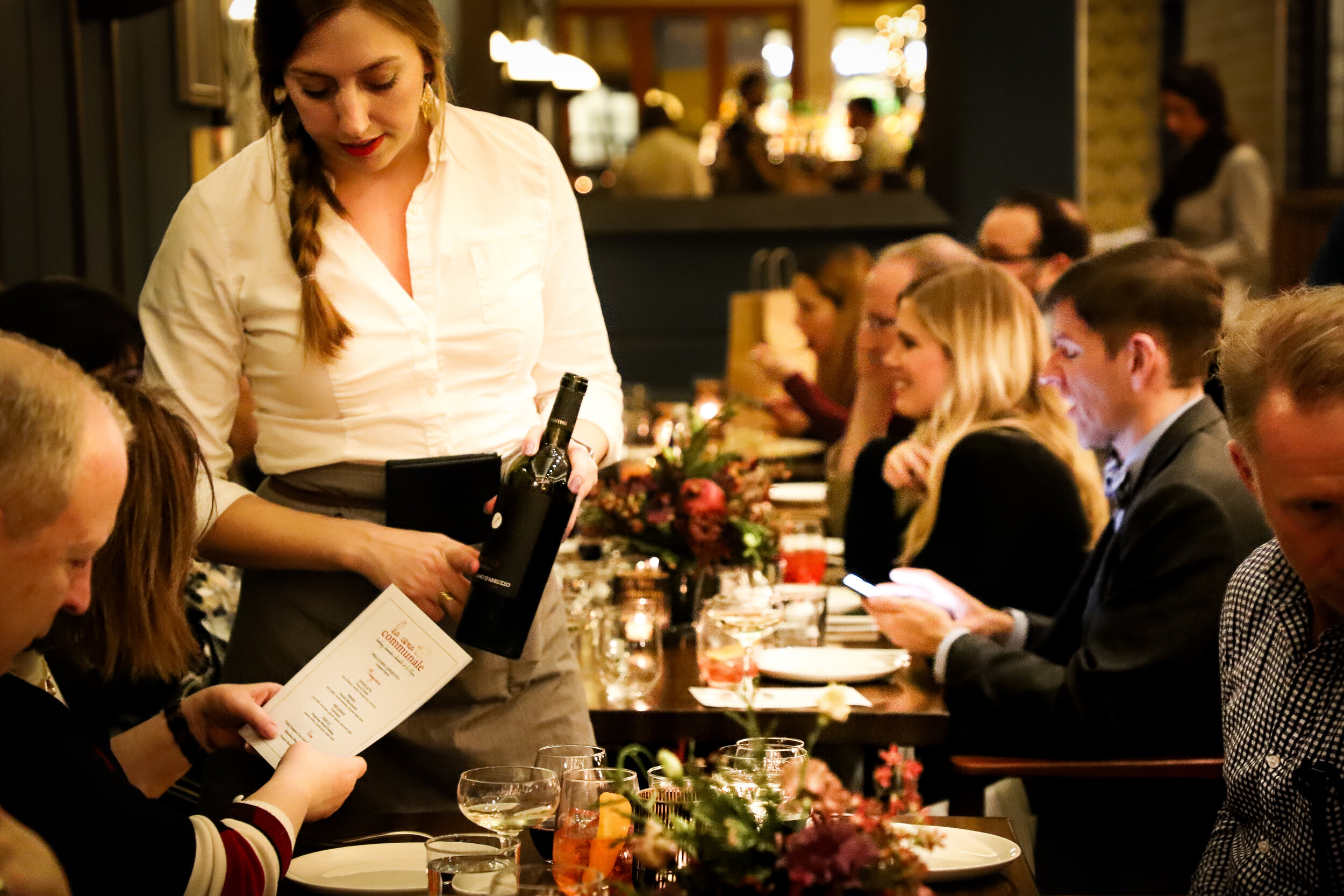 Capture the moment: A server assisting a guest in selecting a wine, presenting the bottle for consideration.