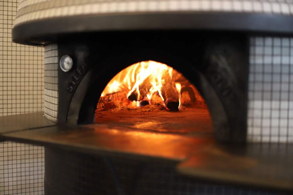 Close-up of our wood-fired pizza oven, the heart of our culinary craftsmanship.