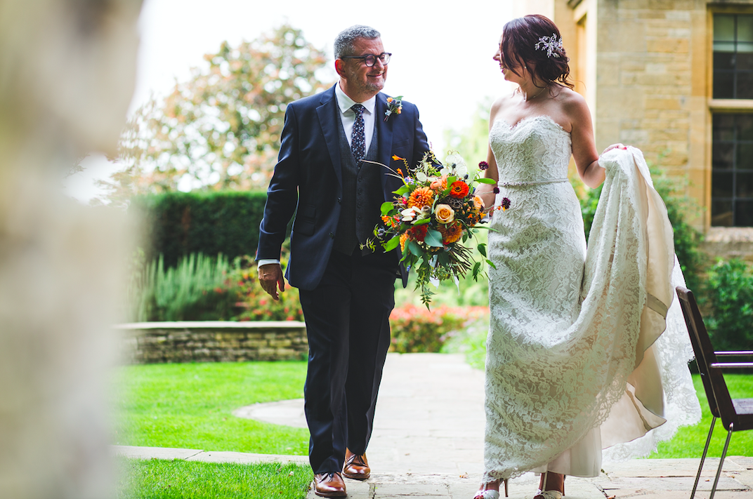 A bridge and groom in a lovely English country garden. the bride is holding a bouquet in autumnal colours and the groom has a matching button hole.