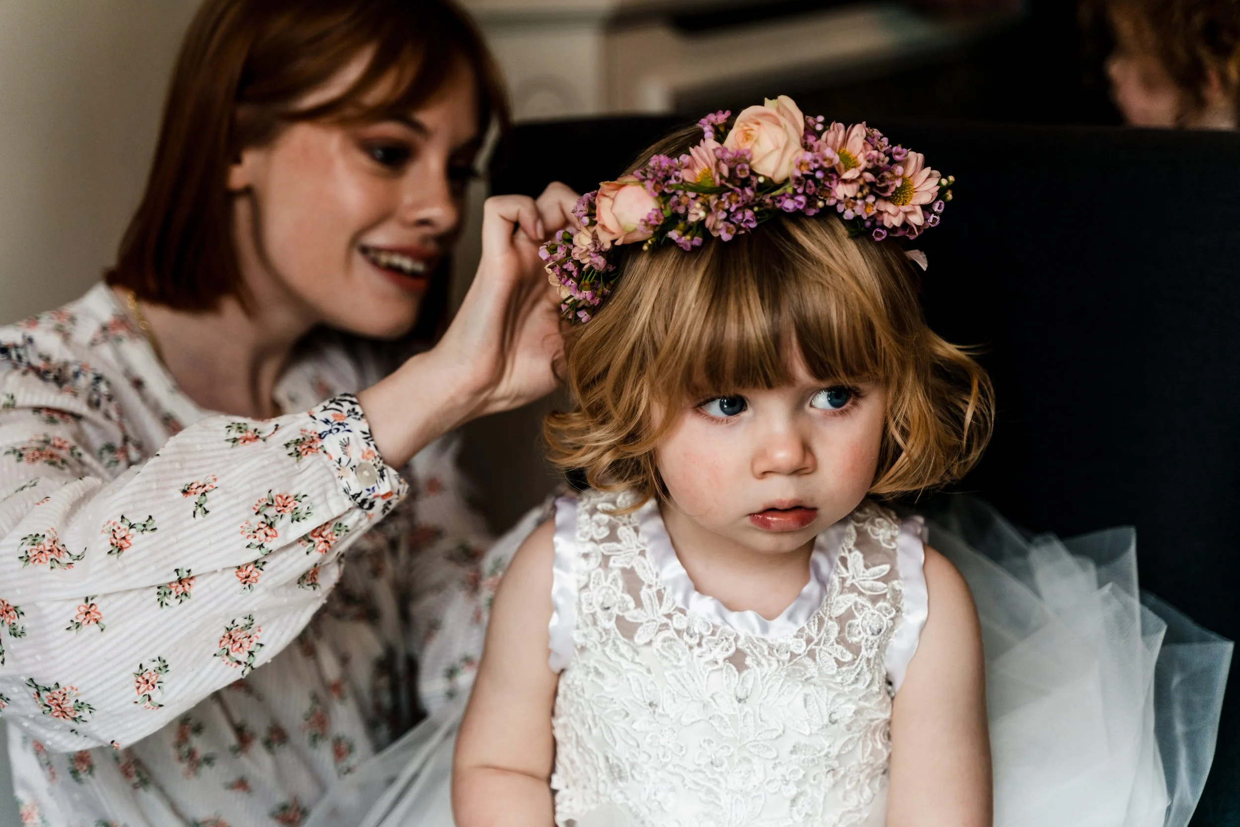 A flower girl having her flower crown fitted. The flower crown is peach roses and pink wax flowers.