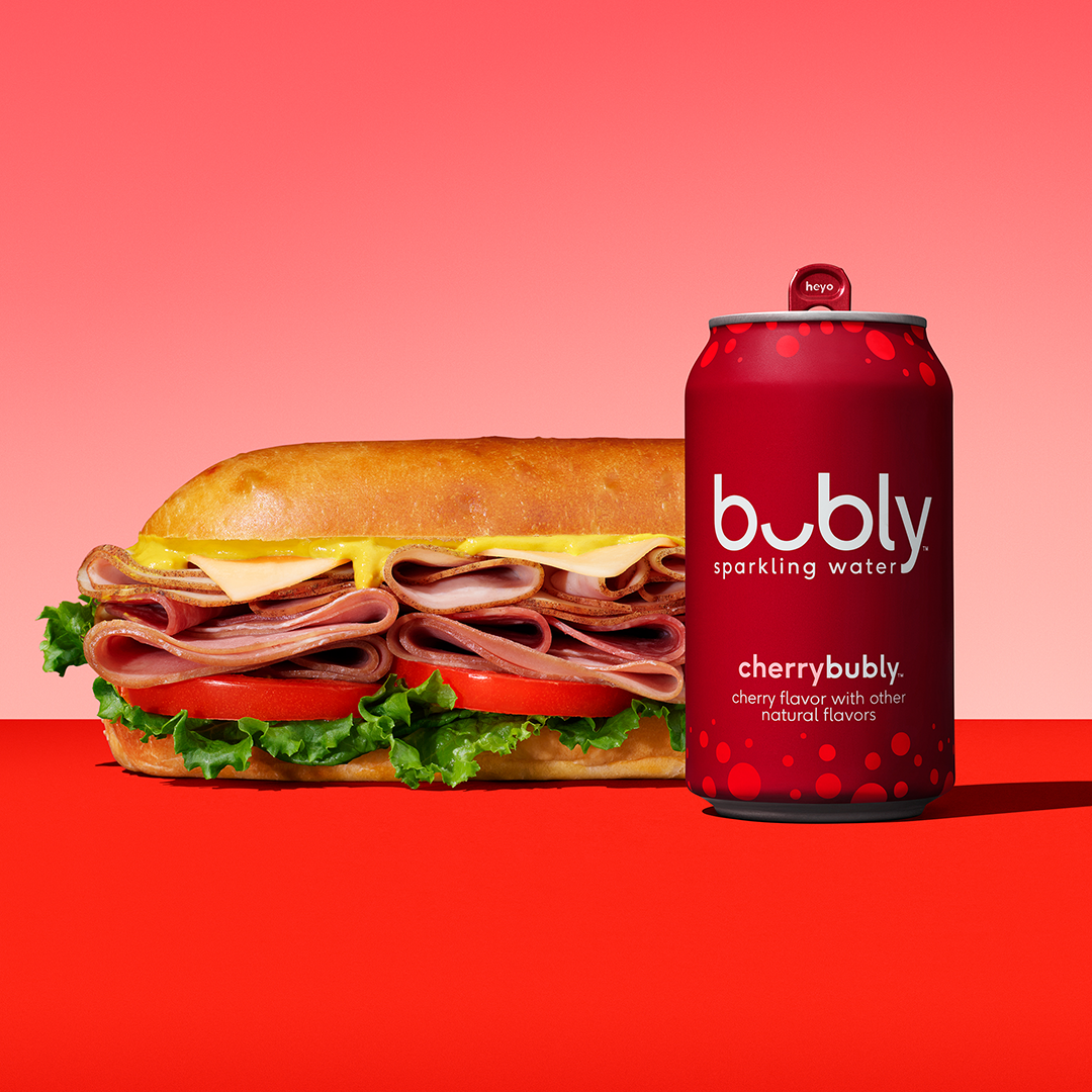 cherry bubly sparkling water can next to sub sandwich