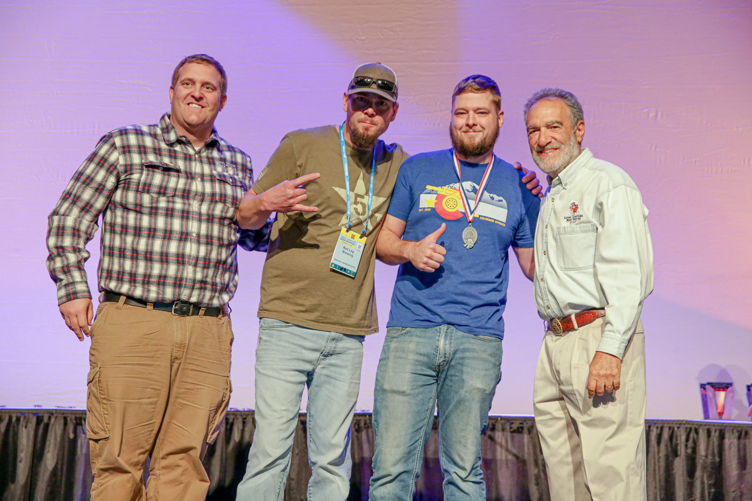 Red Leg’s Todd Baldwin, Troy Johnson and Brendan Hall with Charlie Papazian celebrating their Silver medal win for Howitzer Amber in the German-style Altbier category. Photo © Brewers Association