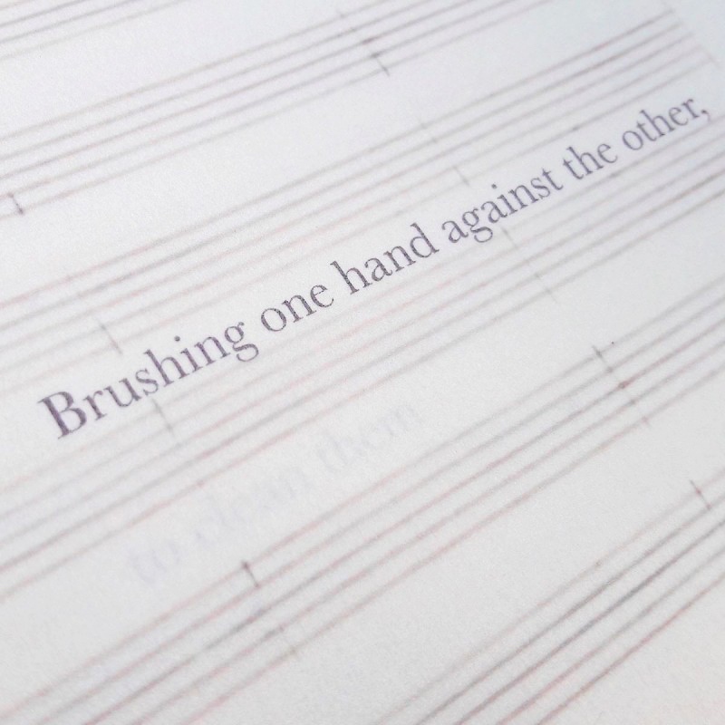 Line from poem overlaid on music staves in handmade artist's book
