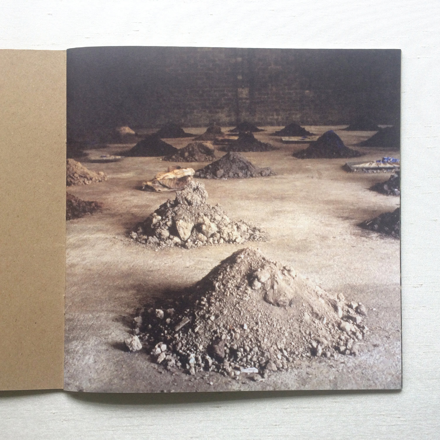 First page in artist Patricia McKenna's catalogue showing heaps of soil on concrete floor