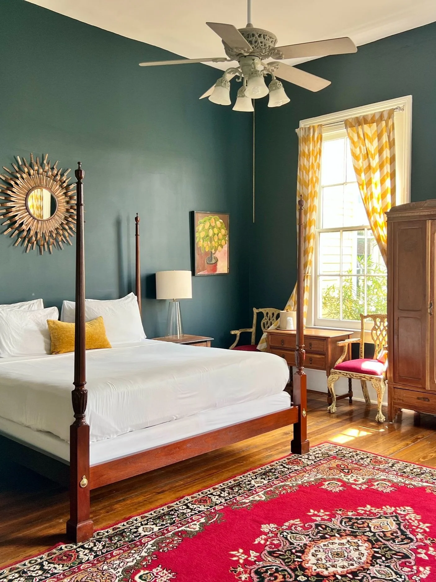 A wide view of a bedroom with a four-poster bed, wooden furniture, and a red rug.