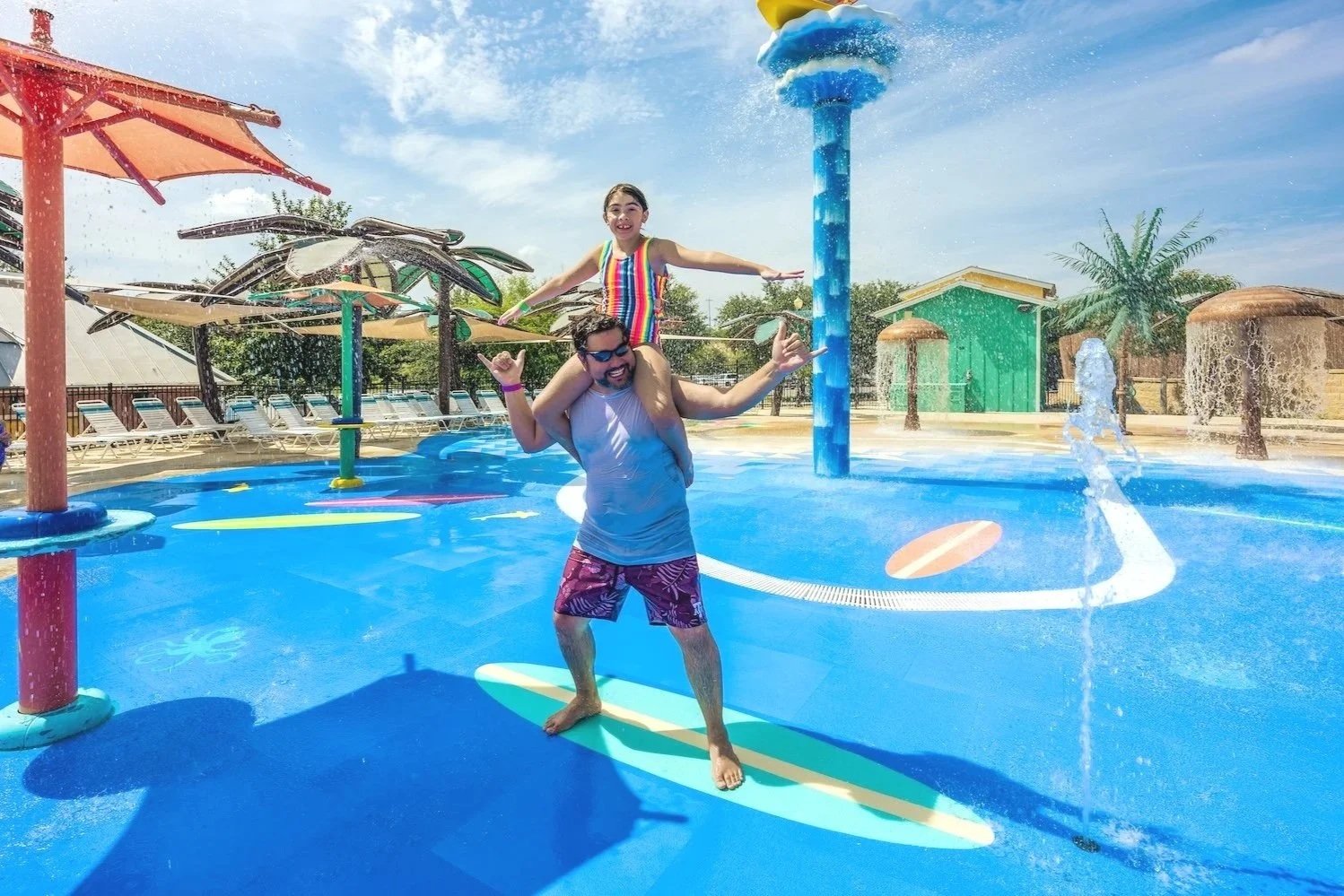Father and daughter playing on surfboard on splash pad with Life Floor, splash pad surfacing