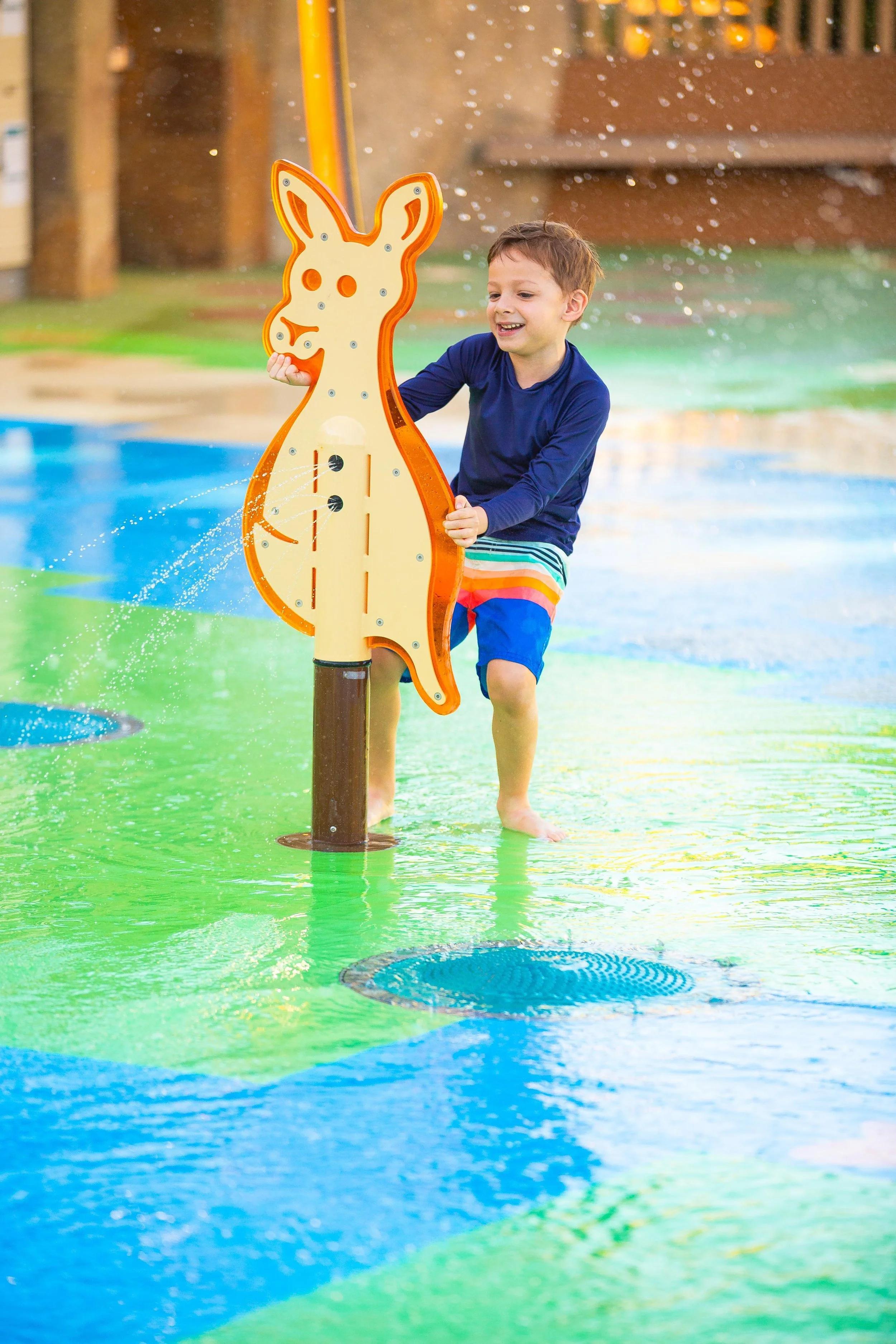 Boy playing on splash pad with aquatic safety surface