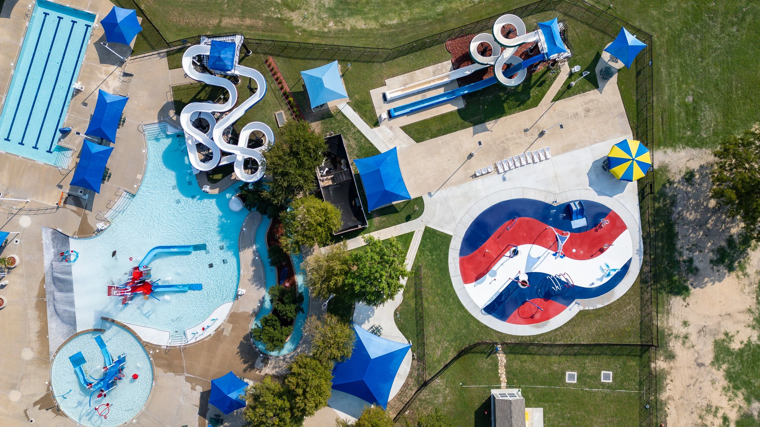 Red, white, and blue Life Floor splash pad surfacing curves across Wet Zone Waterpark in Rowlett, Texas.