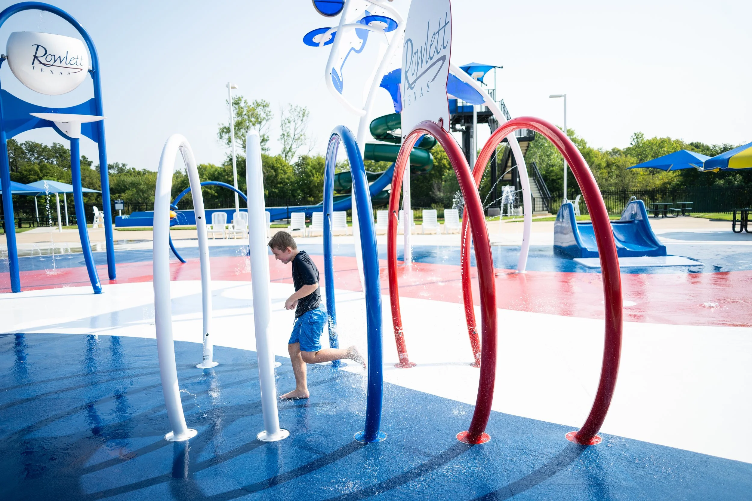 Boy running across patriotic splash pad with Life Floor splash pad surfacing