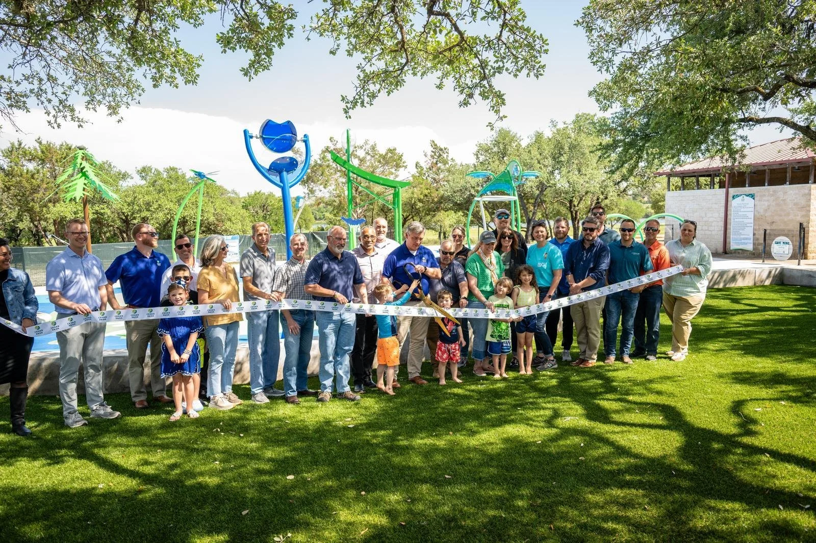 Group of people at Splash Pad grand opening, ribbon cutting ceremony.