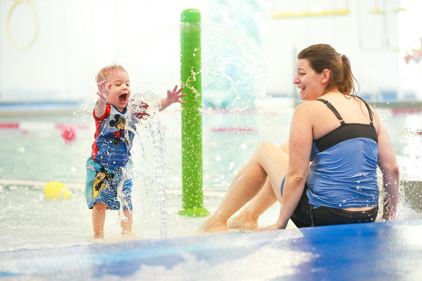 Mom and son playing at indoor pool with safety surfacing