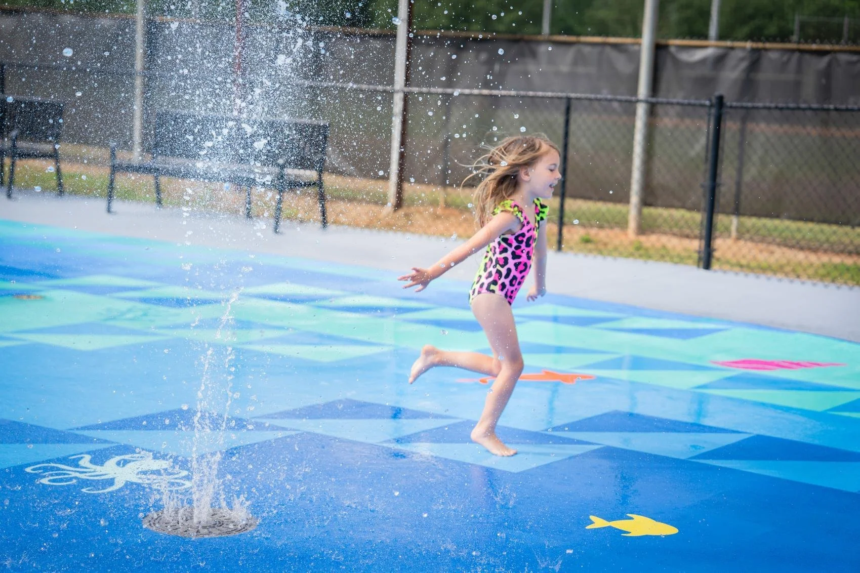 Girl running across splash pad with Life Floor safety surfacing