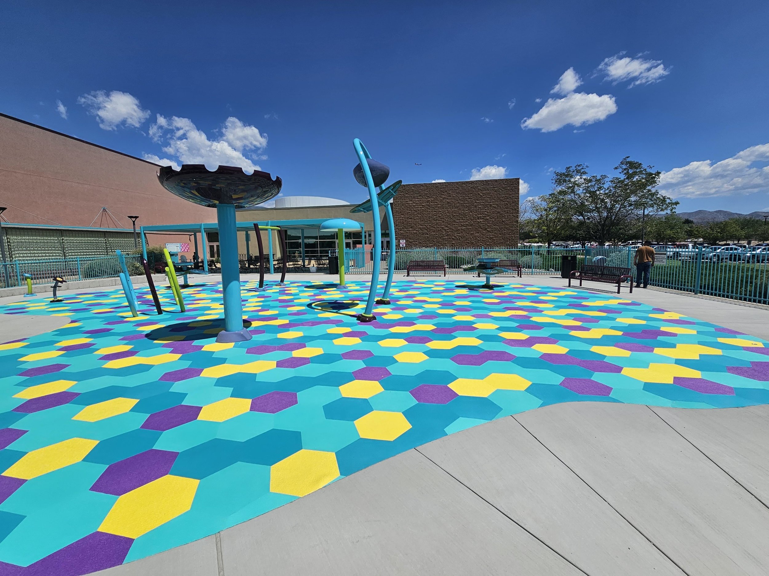 Large splash pad with turquoise, purple, and yellow aquatic safety surfacing. Life Floor non slip pool tiles