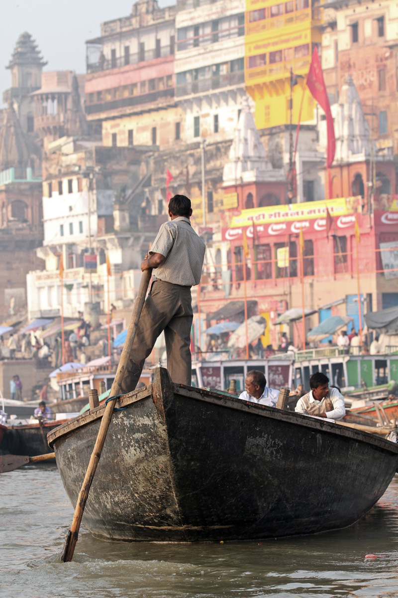 A man steering a boat on the Ganges River in Varanasi, India