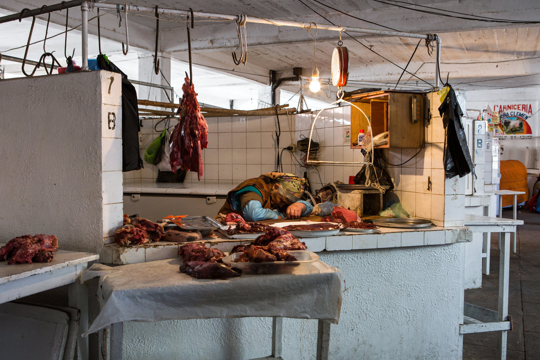 A woman asleep in a market stall selling meat in Bolivia