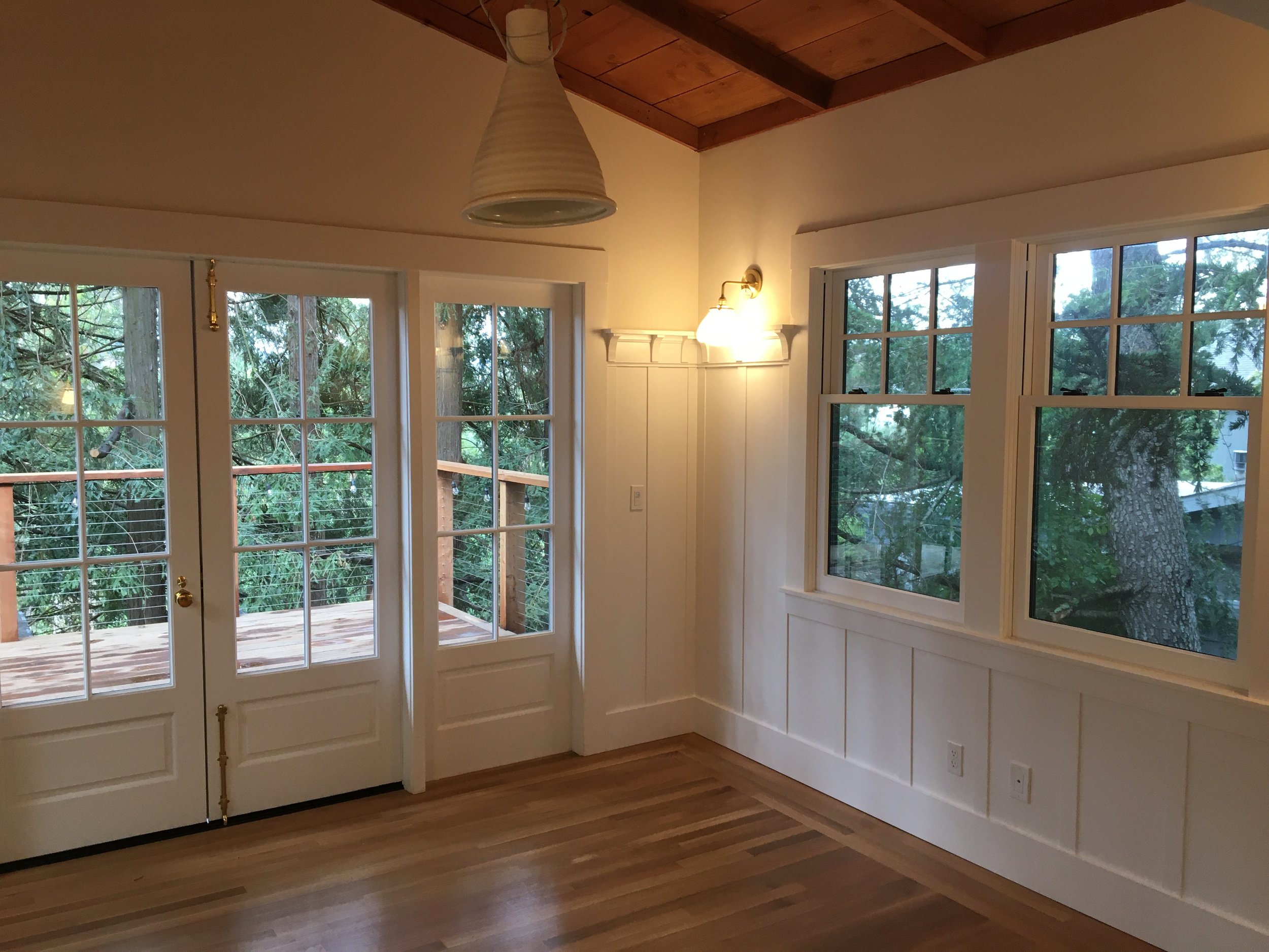  The project also included a back addition, featuring a new dining room with wood paneling and exterior deck surrounded by redwood trees. 