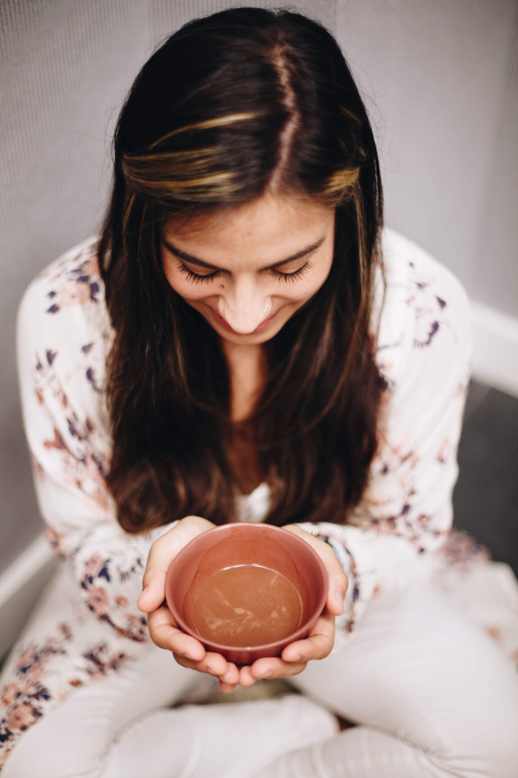 woman in white sitting with a bowl of cacao